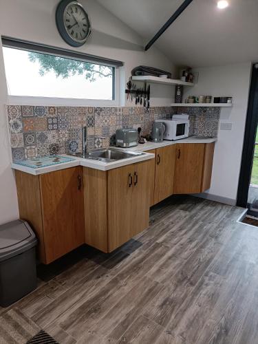 a kitchen with a sink and a clock on the wall at Shed Loft apartment in Longford