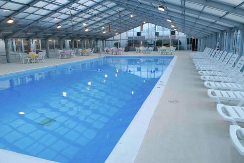 una gran piscina con sillas blancas en un edificio en DoubleTree by Hilton Libertyville-Mundelein, en Mundelein