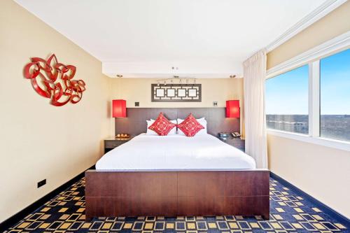 Hilton Suites Chicago/Oakbrook Terrace في أوكبروك تراس: غرفة نوم بسرير كبير ومخدات حمراء