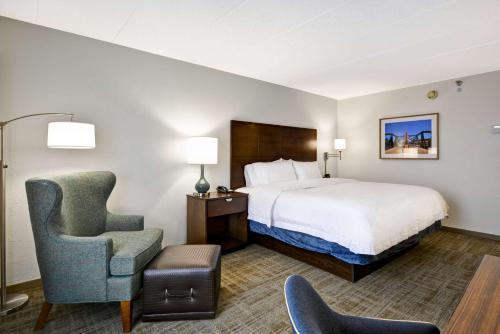 a hotel room with a bed and a chair at Hampton Inn Chicago-Naperville in Naperville