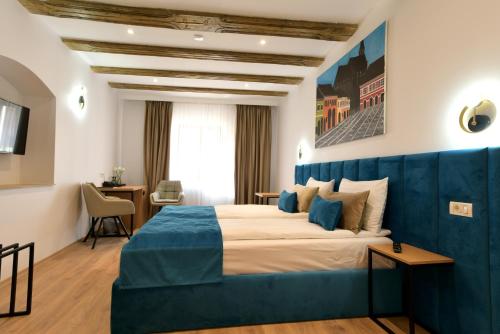 een hotelkamer met een groot bed met een blauw hoofdeinde bij Prinz Gregor in Braşov