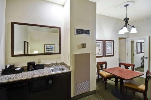 a kitchen and dining room with a sink and a table at Embassy Suites Charleston - Historic District in Charleston