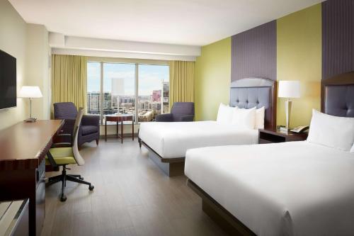 a hotel room with two beds and a desk at Hilton Charlotte Uptown in Charlotte