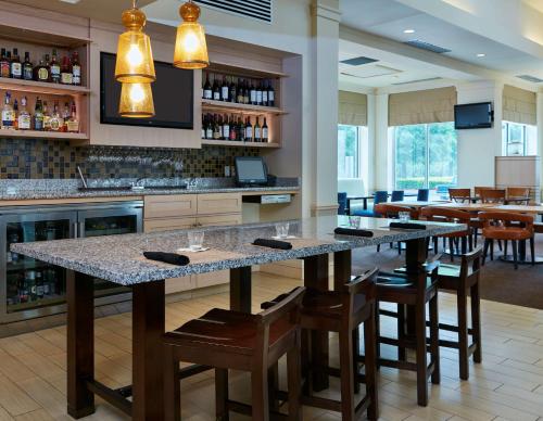a bar in a restaurant with a counter and chairs at Hilton Garden Inn Charlotte Pineville in Charlotte