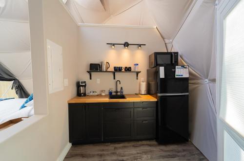 a small kitchen with a black refrigerator in a tent at Gravity Luxury Domes in South Maitland