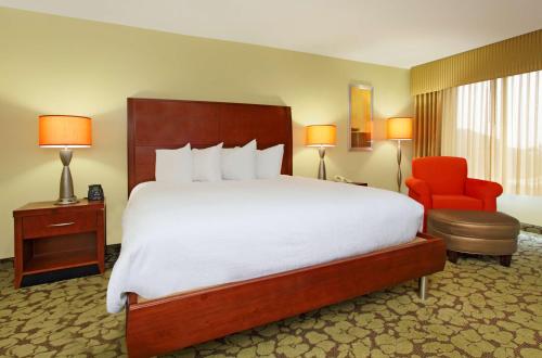 a hotel room with a large bed and a red chair at Hilton Garden Inn Columbus Airport in Columbus