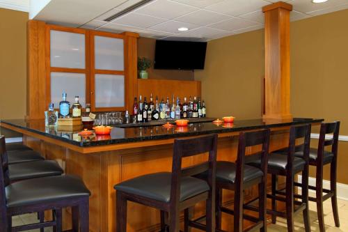a bar with black chairs and bottles of alcohol at Hilton Garden Inn Columbus Airport in Columbus