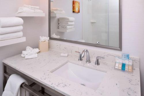 La salle de bains est pourvue d'un lavabo, d'un miroir et de serviettes. dans l'établissement Hilton Garden Inn Columbus/Polaris, à Columbus