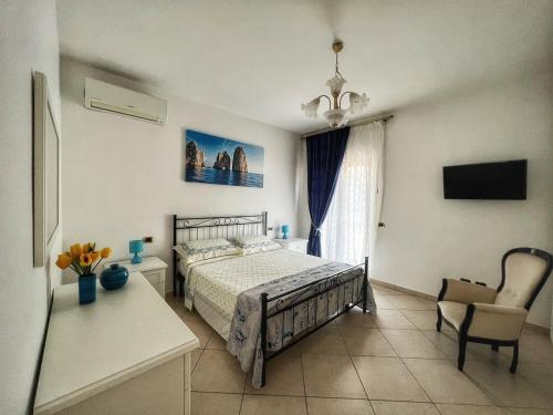 1 dormitorio con 1 cama, 1 silla y TV en Casa Vacanze Villa Marisol, en Vico Equense