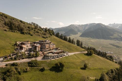 a building on a hill with mountains in the background at DAS GERSTL Alpine Retreat in Malles Venosta