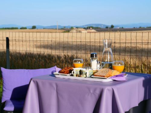 una mesa púrpura con una bandeja de comida y zumo de naranja en Le Spa des lavandes en Valensole