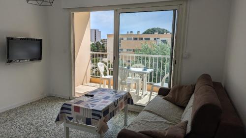 ein Wohnzimmer mit Sofa und Blick auf einen Balkon in der Unterkunft Studio avec coin nuit 150m de la plage in Le Lavandou