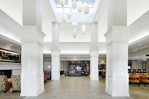 a lobby with white columns and tables and chairs at Hilton Garden Inn Champaign/ Urbana in Champaign