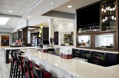 a bar with a white counter and some chairs at Hilton Garden Inn Champaign/ Urbana in Champaign