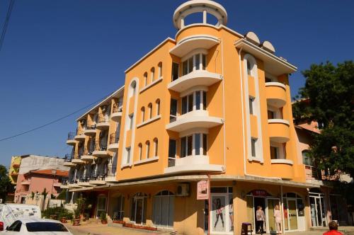 a yellow building with a clock on top of it at Hotel Palma in Burgas