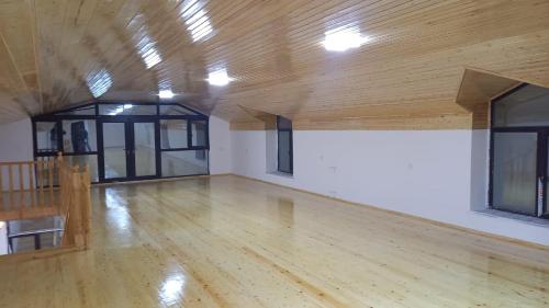 an empty room with a wooden floor and windows at Lahij Rashad Ismayilov Hotel in Lahıc