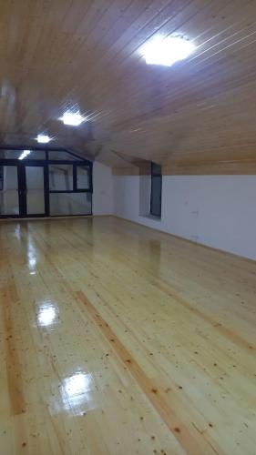 a large empty room with a wooden floor and lights at Lahij Rashad Ismayilov Hotel in Lahıc