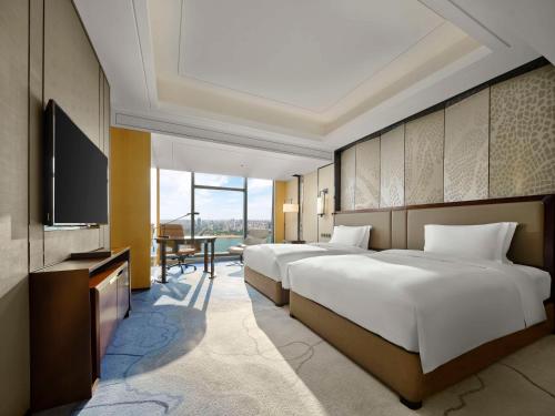 a hotel room with two beds and a flat screen tv at Hilton Zhuzhou in Zhuzhou