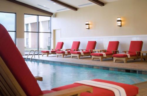 a swimming pool with red chairs in a building at DoubleTree by Hilton Cincinnati Airport in Hebron