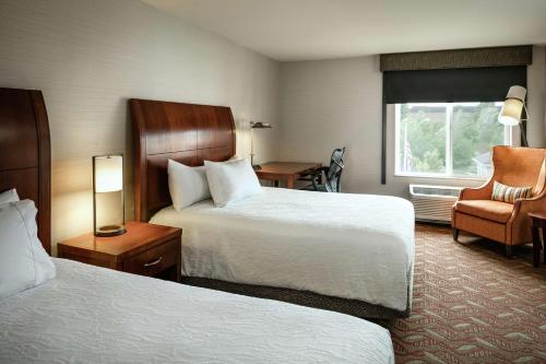 um quarto de hotel com duas camas e uma cadeira em Hilton Garden Inn Corvallis em Corvallis