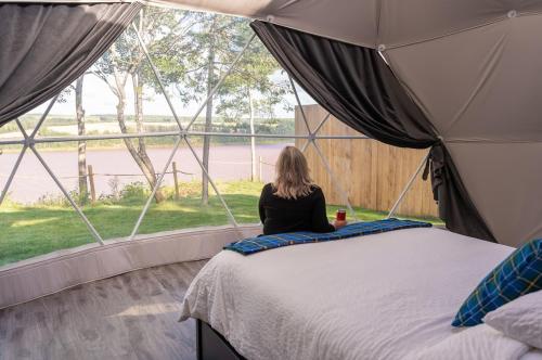South Maitland的住宿－Gravity Luxury Domes，坐在帐篷里,看着窗外的女人
