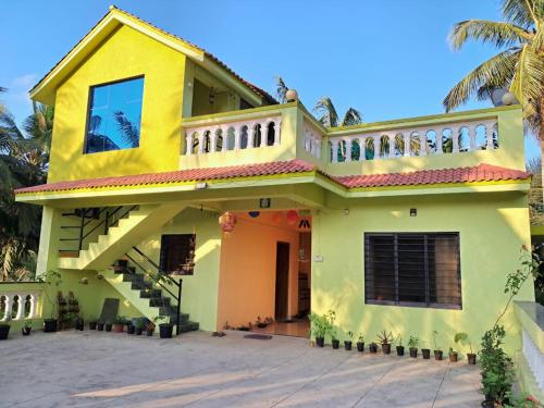 Maison jaune et verte avec balcon dans l'établissement Bageecha B&B-Jal, à Alibaug