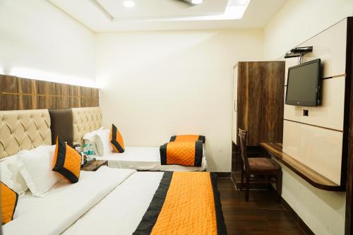a hotel room with a bed and a tv at Hotel Batra Home Nizamuddin in New Delhi