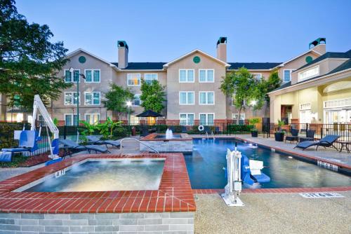 a swimming pool with chairs and a building at Homewood Suites by Hilton Dallas-Lewisville in Lewisville