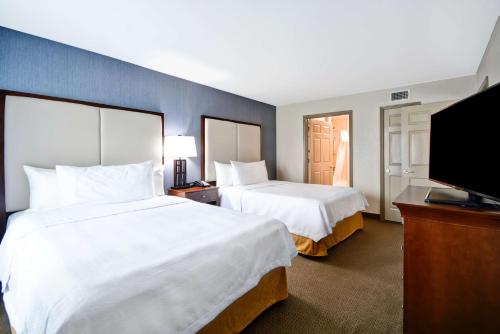 a hotel room with two beds and a flat screen tv at Homewood Suites by Hilton Dallas-Lewisville in Lewisville