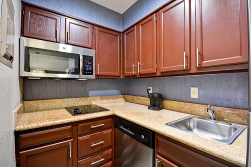 a kitchen with wooden cabinets and a sink and a microwave at Homewood Suites by Hilton Dallas-Lewisville in Lewisville
