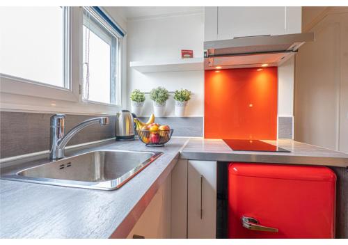 La cuisine est équipée d'un évier et d'un réfrigérateur rouge. dans l'établissement Le Cocon de la Cathédrale, à Évreux