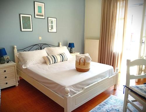 Un dormitorio con una cama blanca con una cesta. en Duka's Gardenhouse, en Skopelos Town