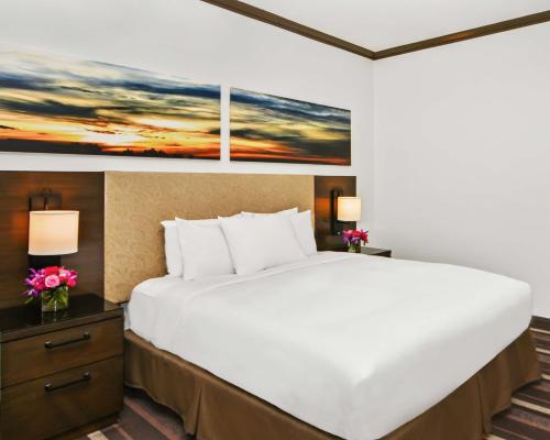 a large bed in a hotel room with a painting on the wall at Hilton Dallas-Park Cities in Dallas