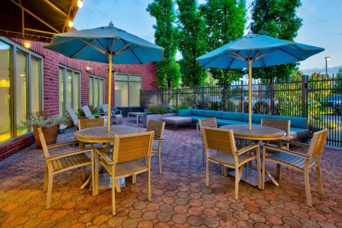 2 mesas y sillas con sombrillas en un patio en Hilton Garden Inn Dayton/ Beavercreek, en Beavercreek