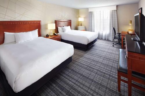 a hotel room with two beds and a flat screen tv at DoubleTree by Hilton Dallas Near the Galleria in Dallas