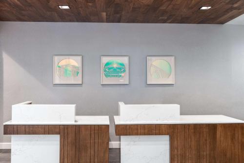 three framed paintings on a wall with two tables at Hilton Garden Inn Arlington/Courthouse Plaza in Arlington