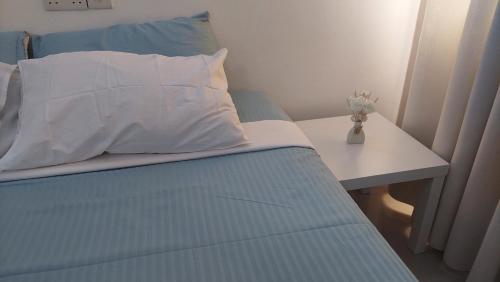 a bed with a table and a white pillow on it at Sami BnB - Apt 01 Makongo after Mlimani City in Dar es Salaam