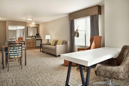 a hotel room with a desk and a living room at Hilton Garden Inn Dubuque Downtown in Dubuque