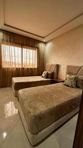 アガディールにあるAppartement Anirのベッド2台と窓が備わるホテルルームです。