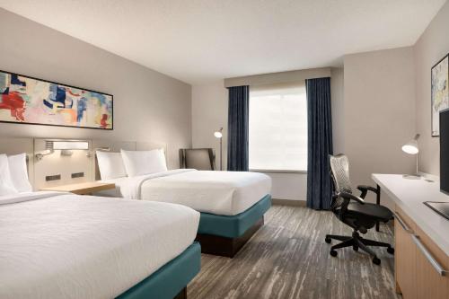 a hotel room with two beds and a desk at Hilton Garden Inn Tysons Corner in Tysons Corner