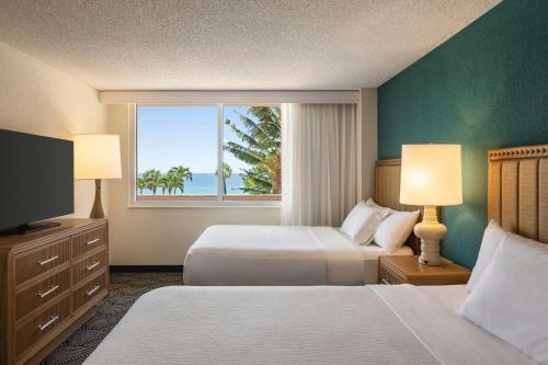 a hotel room with two beds and a window at Embassy Suites by Hilton Deerfield Beach Resort & Spa in Deerfield Beach