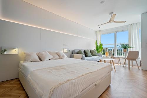 a white bedroom with a bed and a living room at Hauzify I Loft Ancora in La Pineda