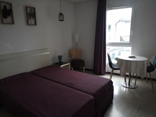 une chambre avec un lit, une table et une fenêtre dans l'établissement Agréable Studio familial à lourdes, proche gare, à Lourdes