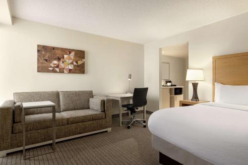 a hotel room with a bed and a couch and a desk at Embassy Suites by Hilton Denver International Airport in Denver