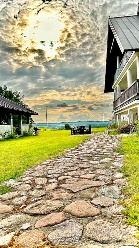 a stone walkway next to a house and a building at Cisowe Sioło in Jeleniewo
