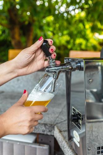 a woman pouring a glass of beer from a grill at Private summer house with swimming pool, beach bar and pit for football and volleyball in Hvězdonice