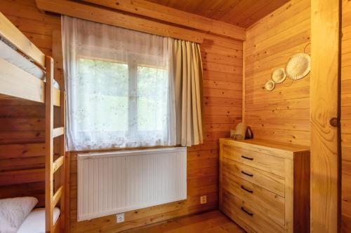 a bedroom with a bunk bed and a window at Private summer house with swimming pool, beach bar and pit for football and volleyball in Hvězdonice