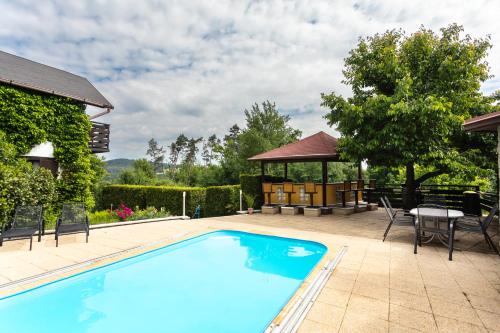 a swimming pool with a table and chairs and a gazebo at Private summer house with swimming pool, beach bar and pit for football and volleyball in Hvězdonice