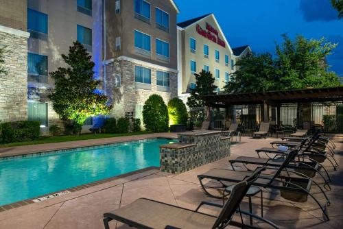 a hotel patio with a swimming pool and chairs at Hilton Garden Inn Denton in Denton
