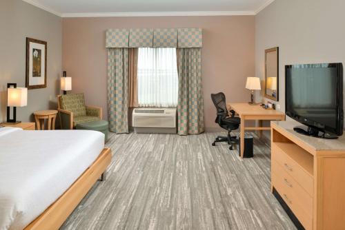 ein Hotelzimmer mit einem Bett und einem Flachbild-TV in der Unterkunft Hilton Garden Inn Denton in Denton
